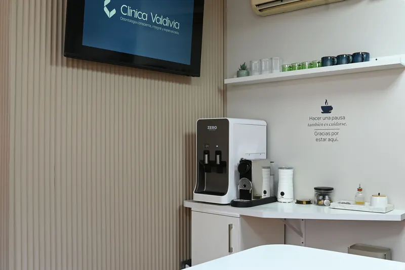 Rincón de café para pacientes con una pantalla de Clínica Valdivia